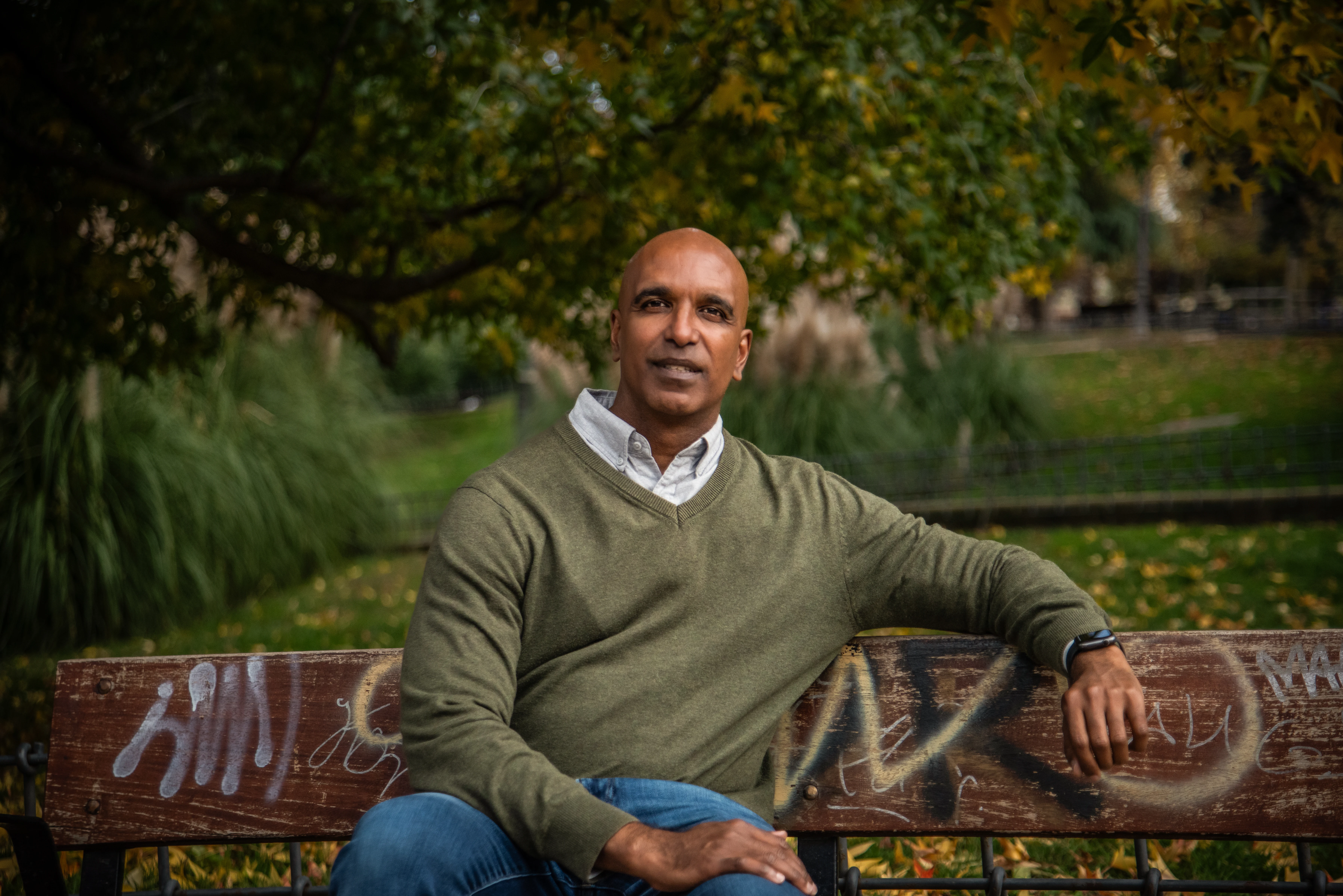 Merlin Ince seated on a bench in autumn light